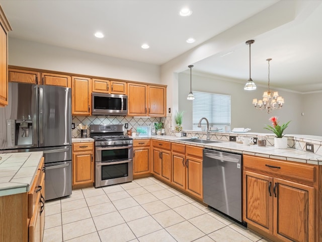 kitchen featuring tile countertops, stainless steel appliances, a notable chandelier, sink, and ornamental molding