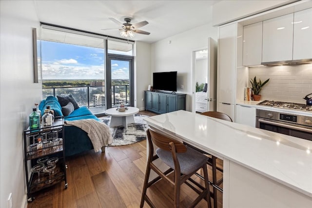 44 E Ave Unit 1709, Austin, TX 78701 - kitchen with stainless steel appliances, a breakfast bar area, tasteful backsplash, white cabinets, and wood finished floors