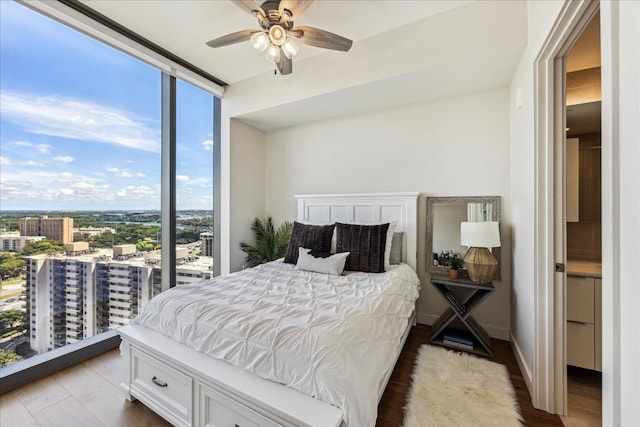 bedroom with ceiling fan, hardwood / wood-style floors, and a wall of windows