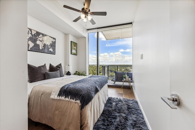 bedroom featuring wood-type flooring, expansive windows, and ceiling fan