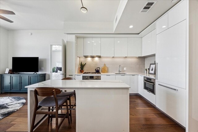 kitchen featuring ceiling fan, white cabinetry, a center island, and stainless steel oven