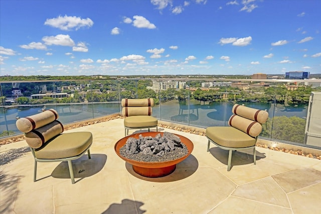 balcony with a fire pit, a water view, and a patio