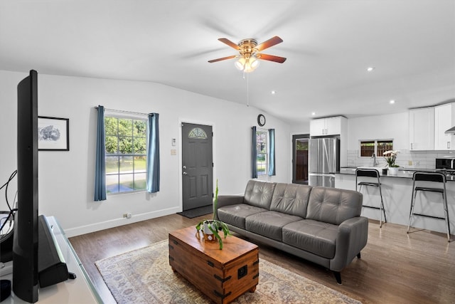 living room with ceiling fan, vaulted ceiling, and light hardwood / wood-style floors