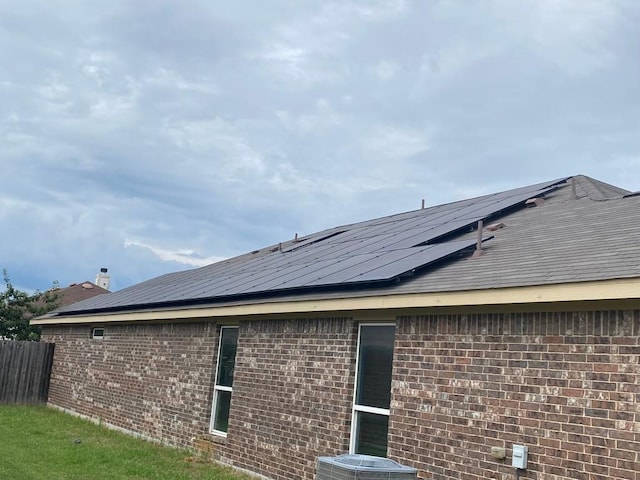 view of home's exterior with brick siding, roof mounted solar panels, and central air condition unit