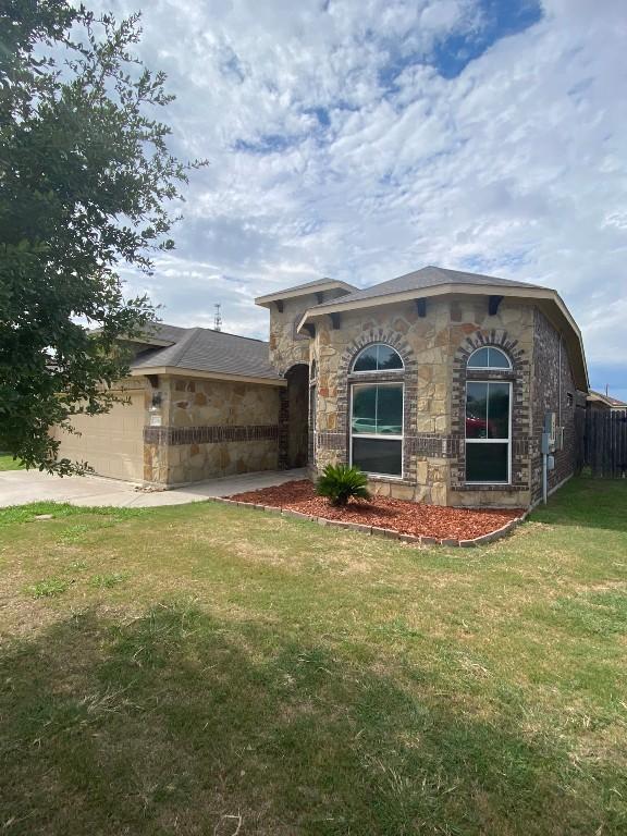 view of front of house with a garage, concrete driveway, a front yard, and stone siding