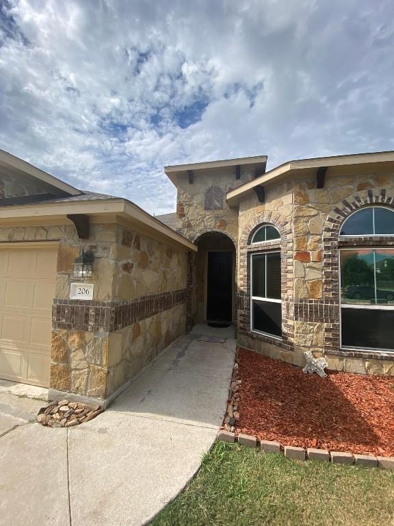 view of exterior entry featuring an attached garage and stone siding