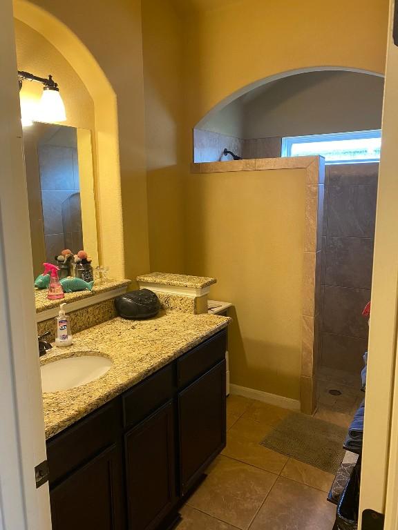 full bath featuring tile patterned flooring, baseboards, vanity, and walk in shower