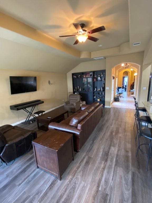 living room featuring visible vents, wood finished floors, arched walkways, ceiling fan, and vaulted ceiling