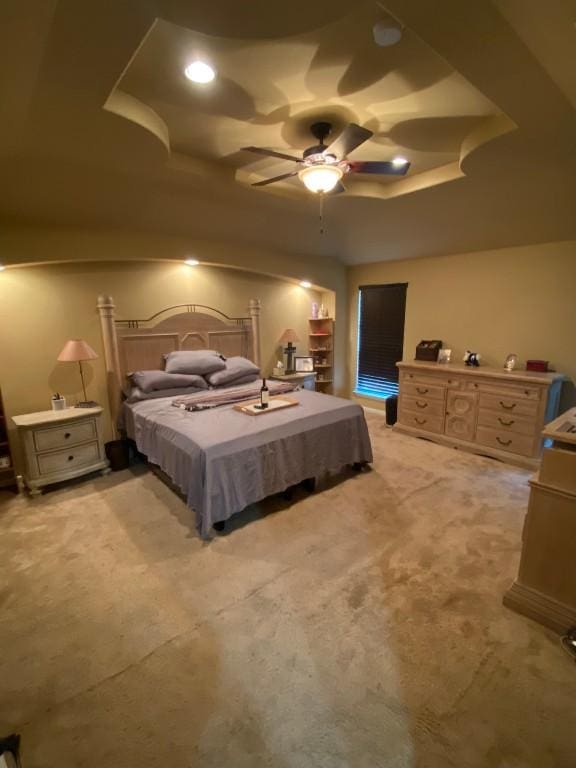 bedroom with a tray ceiling, light carpet, and ceiling fan