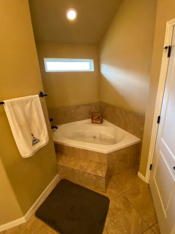 bathroom featuring a tub with jets, vaulted ceiling, and tile patterned flooring