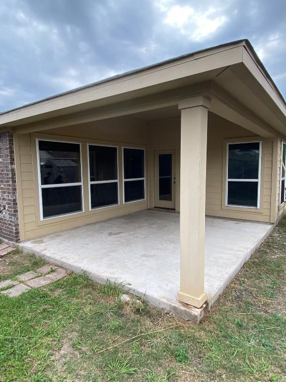 back of property featuring a patio and brick siding