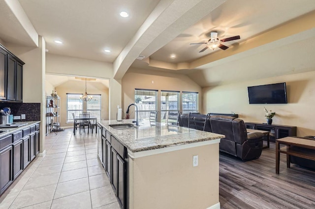 206 Swenson Dr, Hutto, TX 78634 - kitchen with a chandelier, open floor plan, light stone countertops, decorative backsplash, and a center island with sink