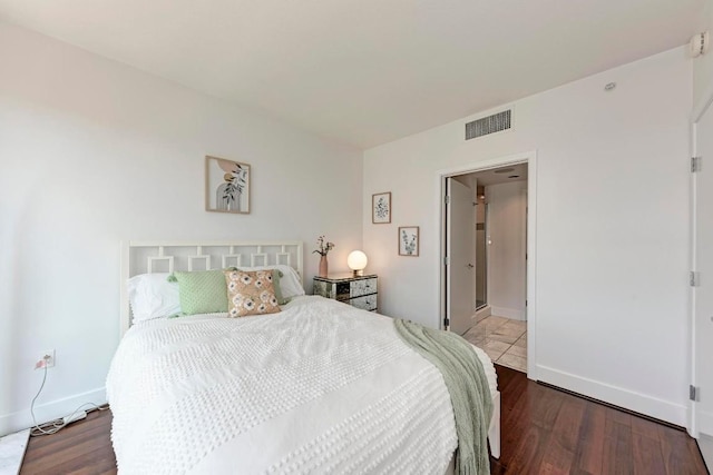 bedroom with wood finished floors, visible vents, and baseboards