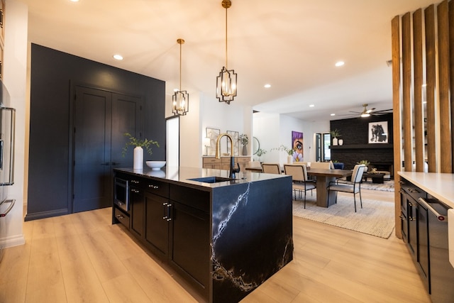 kitchen with ceiling fan with notable chandelier, decorative light fixtures, light hardwood / wood-style floors, and sink