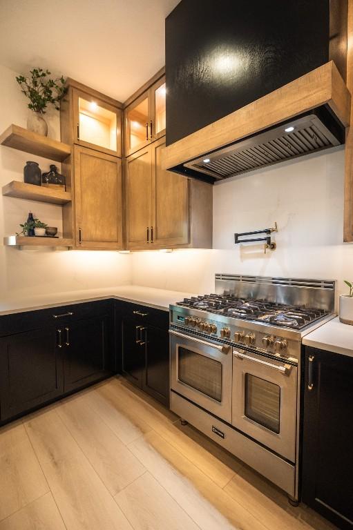 kitchen featuring double oven range, custom range hood, and light wood-type flooring