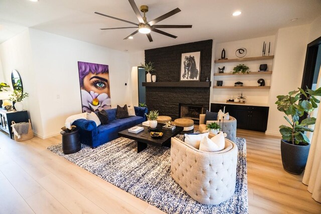 living room featuring a fireplace, light wood-type flooring, and ceiling fan