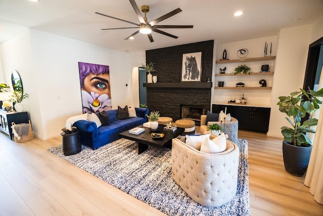 living area featuring recessed lighting, a fireplace, a ceiling fan, baseboards, and light wood finished floors