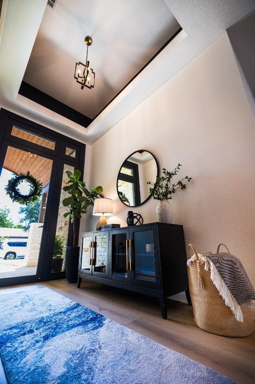 entrance foyer with a chandelier, a tray ceiling, and wood finished floors