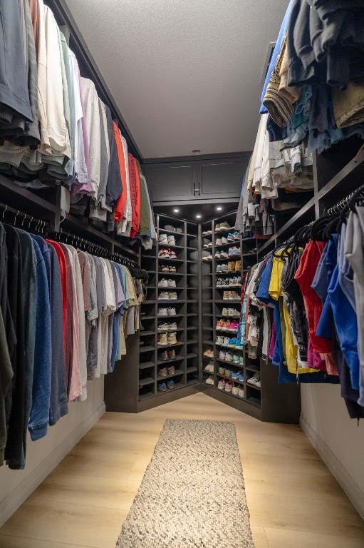 walk in closet with light hardwood / wood-style floors