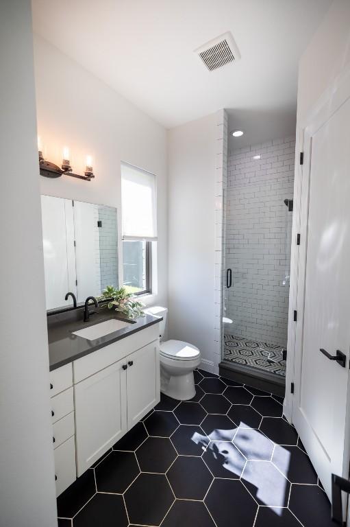 bathroom featuring toilet, a stall shower, visible vents, and vanity