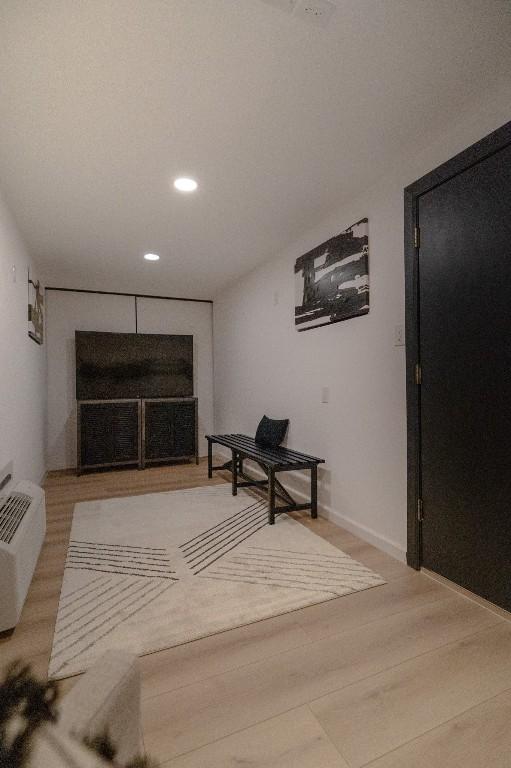 hall with light wood-style floors, recessed lighting, a wall mounted air conditioner, and baseboards