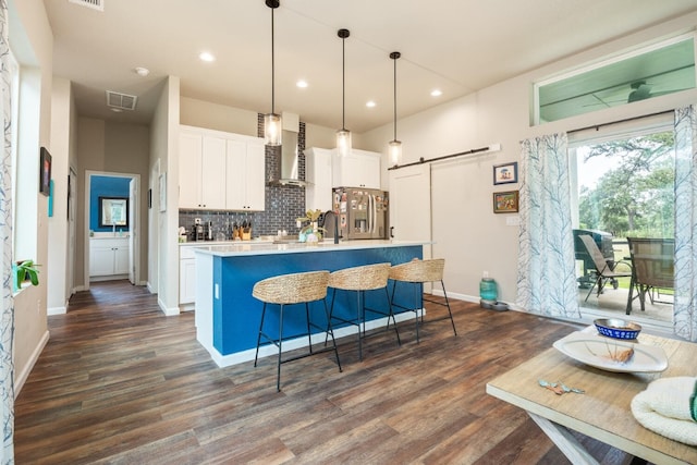 103 Hans Bell Dr, Blanco, TX 78606 - kitchen with stainless steel refrigerator with ice dispenser, wall chimney exhaust hood, a barn door, white cabinetry, and decorative backsplash