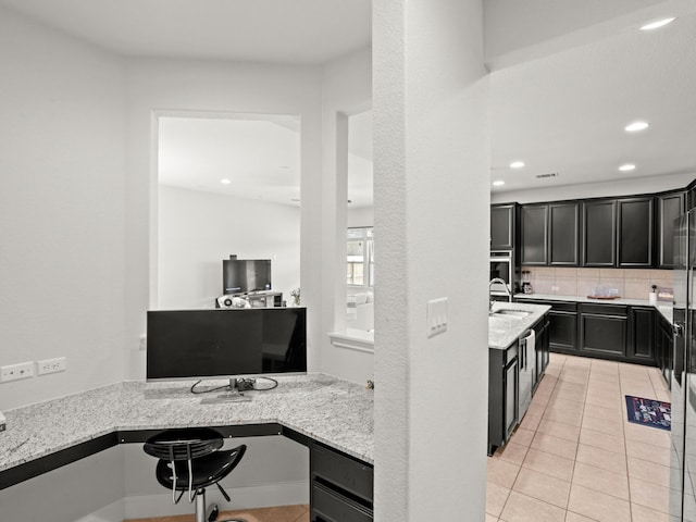 kitchen with backsplash, light stone countertops, kitchen peninsula, and light tile patterned floors