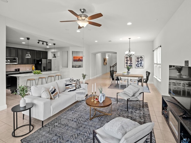 tiled living room with ceiling fan with notable chandelier