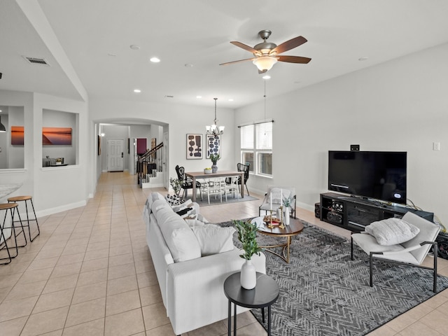 tiled living room featuring ceiling fan with notable chandelier and built in features