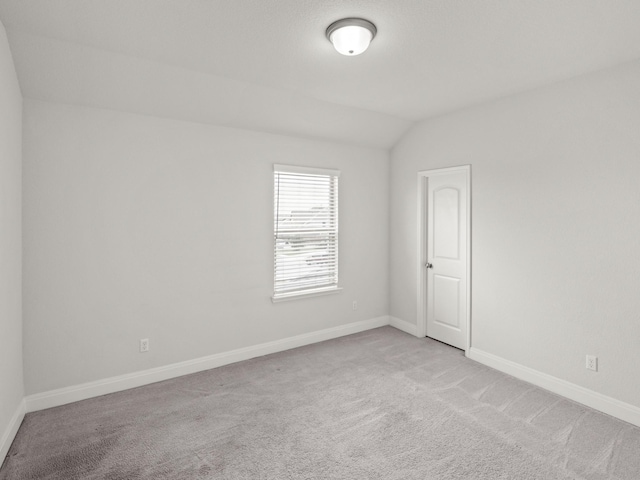 carpeted spare room featuring lofted ceiling