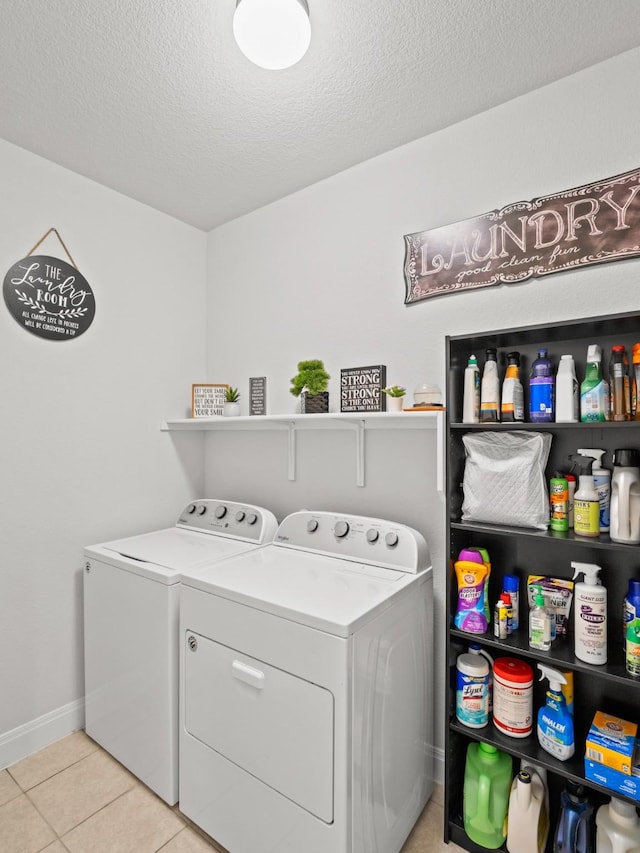 washroom with a textured ceiling, washer and dryer, and light tile patterned floors