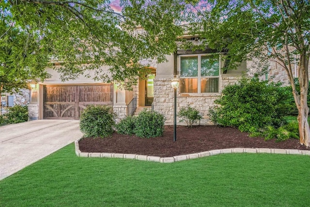 view of front of house featuring driveway, stone siding, a front lawn, and stucco siding