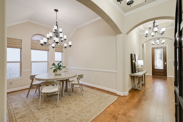 dining space featuring lofted ceiling, light wood-style flooring, an inviting chandelier, ornamental molding, and baseboards