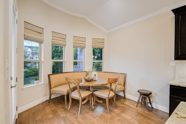 dining space featuring vaulted ceiling, light wood-type flooring, baseboards, and crown molding