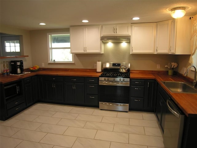 kitchen featuring wood counters, stainless steel appliances, sink, white cabinets, and light tile patterned flooring