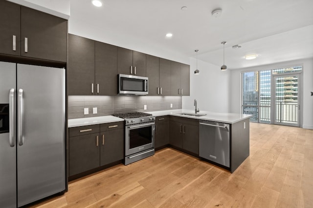 kitchen featuring pendant lighting, light wood-type flooring, sink, and appliances with stainless steel finishes