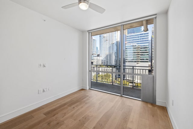 unfurnished room with ceiling fan, light hardwood / wood-style floors, and a wall of windows