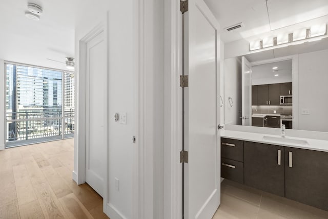 bathroom with floor to ceiling windows, ceiling fan, backsplash, vanity, and hardwood / wood-style flooring