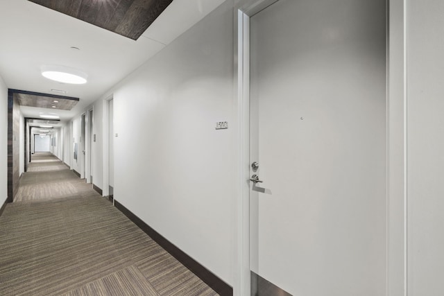 corridor featuring dark colored carpet