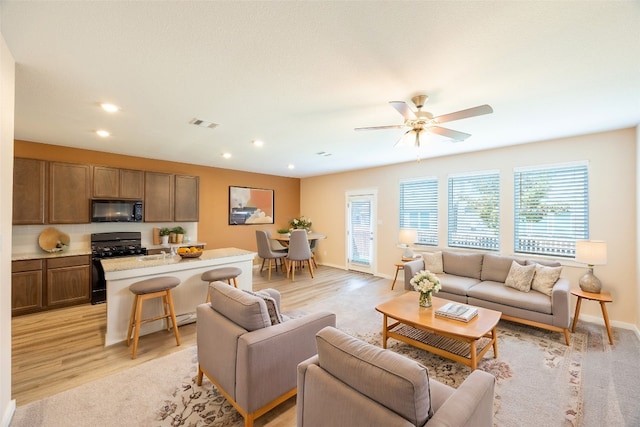 living room with light wood-type flooring and ceiling fan