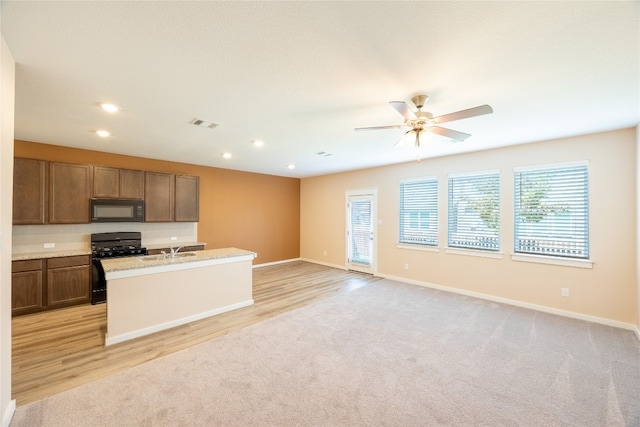 kitchen with black appliances, ceiling fan, sink, and light hardwood / wood-style floors