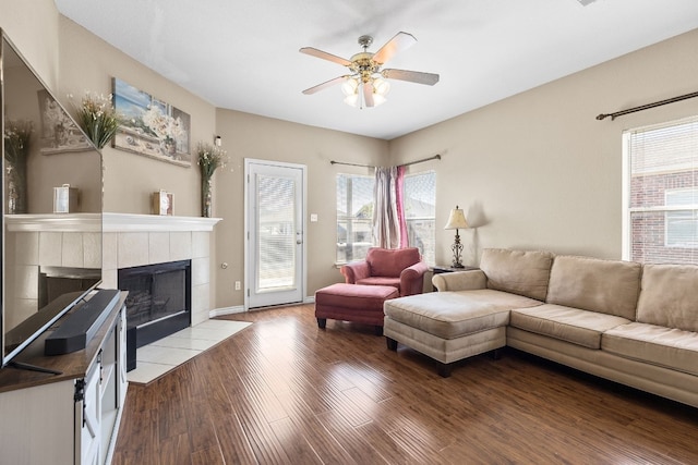 living room with a tiled fireplace, ceiling fan, and dark hardwood / wood-style floors