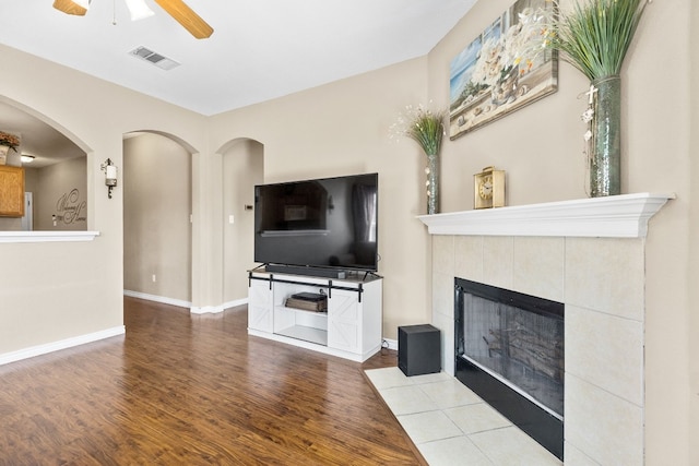 unfurnished living room featuring hardwood / wood-style floors, ceiling fan, and a fireplace