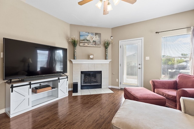 living room featuring ceiling fan, a tile fireplace, and hardwood / wood-style flooring