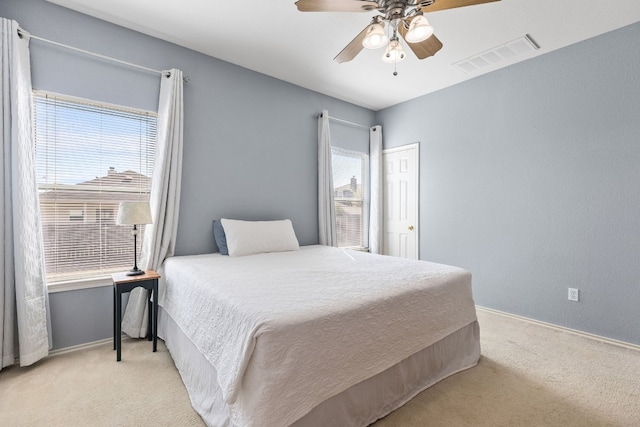 bedroom with multiple windows, ceiling fan, and light colored carpet