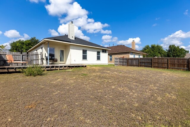 back of property featuring a yard and a deck