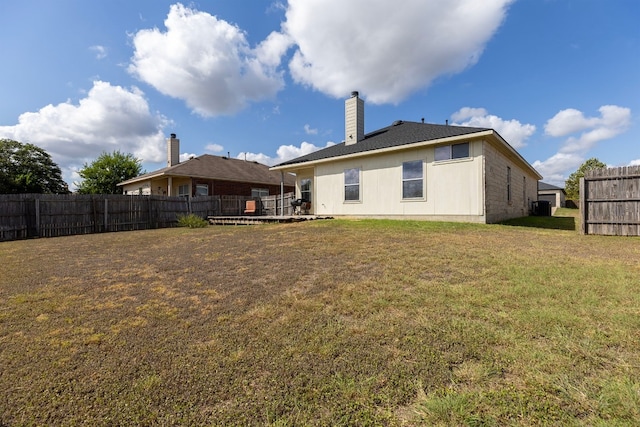 rear view of house featuring a lawn and a wooden deck