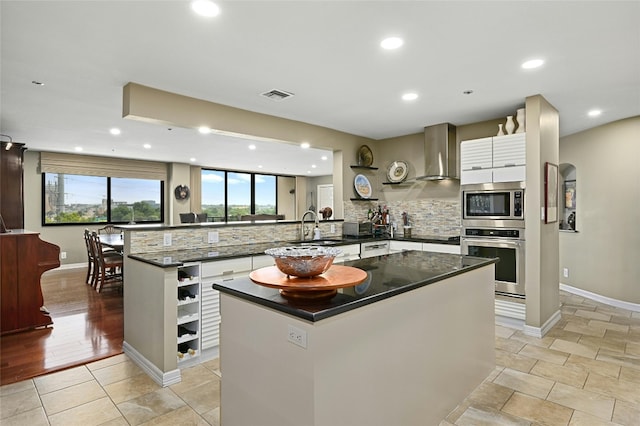 40 N Interstate Highway 35 Unit 8C1, Austin, TX 78701 - kitchen featuring appliances with stainless steel finishes, a peninsula, decorative backsplash, white cabinets, and wall chimney range hood
