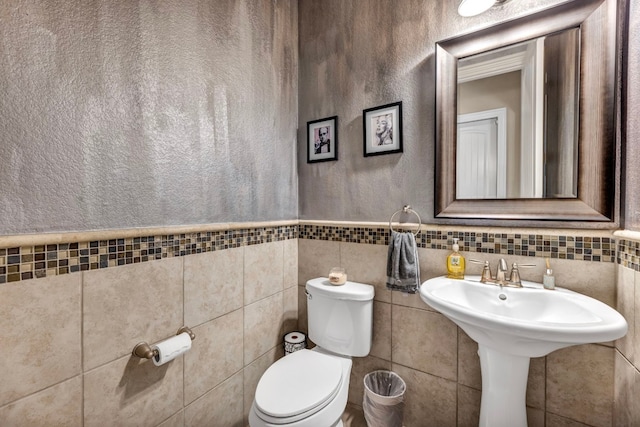 bathroom with tile walls, toilet, and backsplash