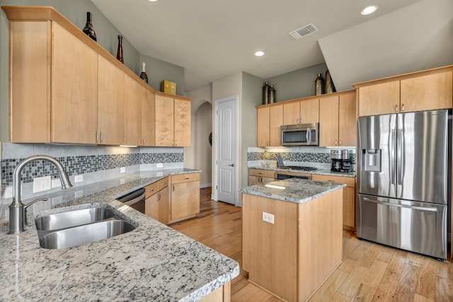 kitchen featuring appliances with stainless steel finishes, light hardwood / wood-style flooring, and light stone countertops